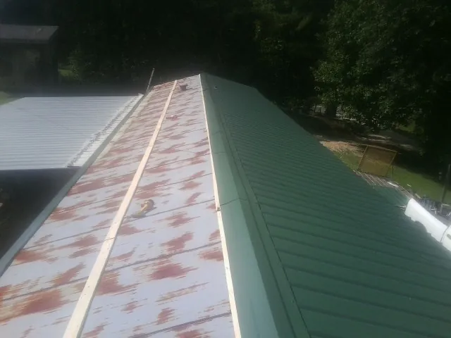Old rusted panels beside newly installed green metal roofing — Wind Damage Roof Repair by Roofing Brothers in Knightdale
