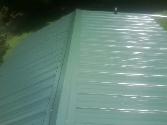 New green metal panels meeting at the ridge of a roof — Flat Roof Repair work by our crew in Knightdale