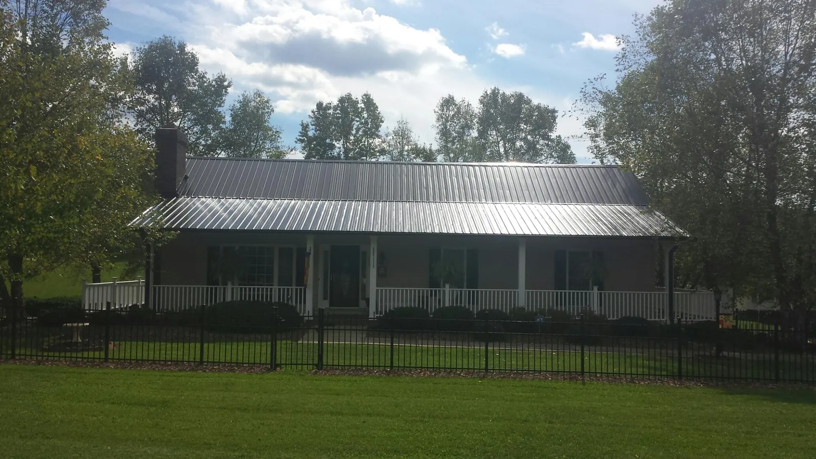 Gray metal roof on a brick ranch with a full width front porch — Gutter Guard Installation work by our crew in Knightdale