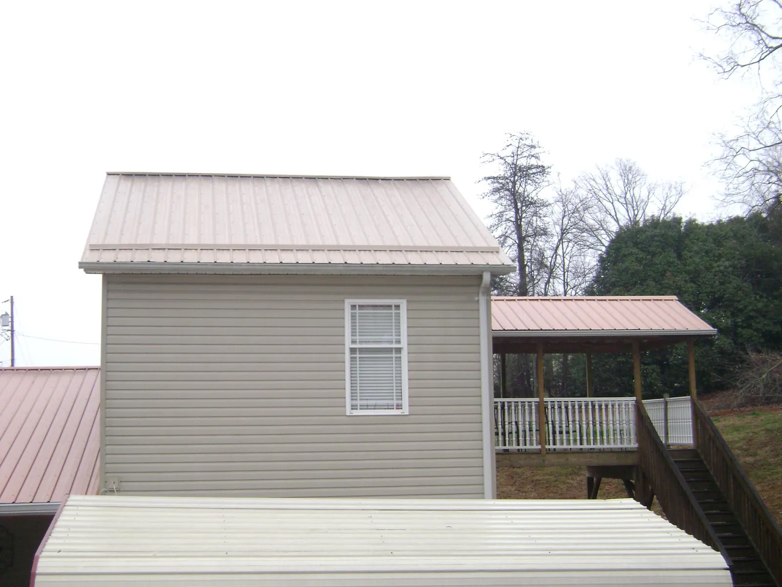 Tan metal roofs on a two story addition and attached porch, from a Roof Replacement job in Knightdale