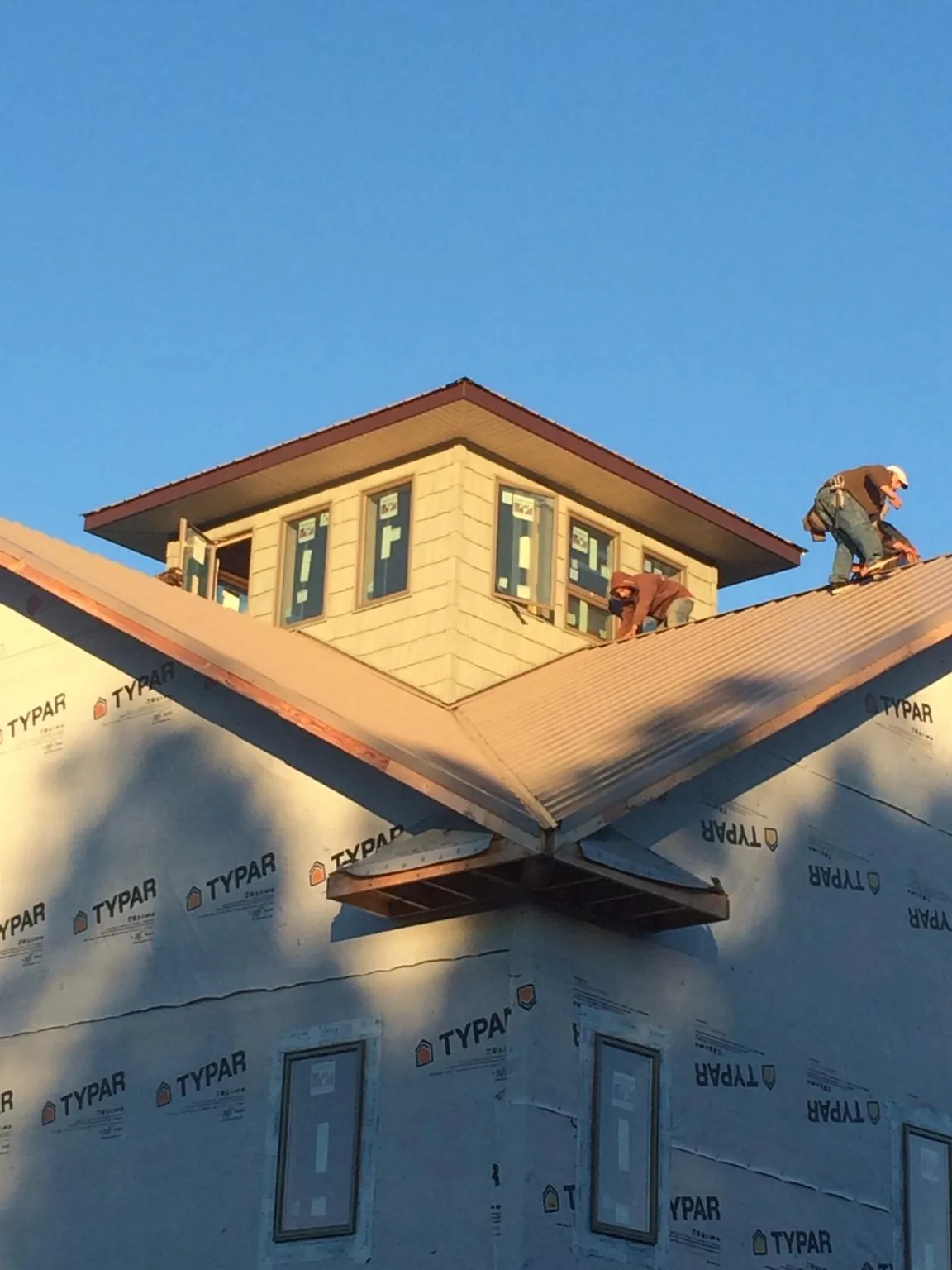 Roofers working around a rooftop cupola on a new metal roof at sunset — Roof Waterproofing in Knightdale by Roofing Brothers